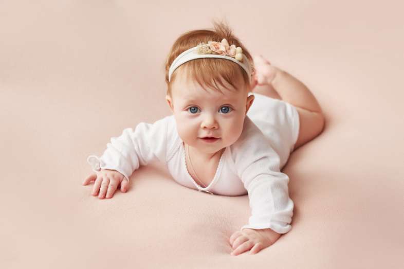 girl-four-months-lies-light-pink-background